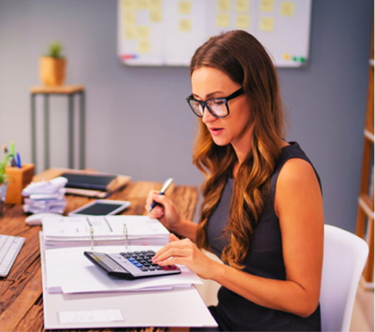 Woman working at desk with financial documents.