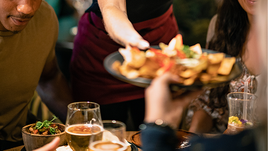 Food being served at restaurant table.